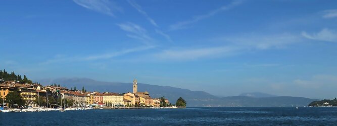 Trip Balearen beliebte Urlaubsziele am Gardasee -  Mit einer Fläche von 370 km² ist der Gardasee der größte See Italiens. Es liegt am Fuße der Alpen und erstreckt sich über drei Staaten: Lombardei, Venetien und Trentino. Die maximale Tiefe des Sees beträgt 346 m, er hat eine längliche Form und sein nördliches Ende ist sehr schmal. Dort ist der See von den Bergen der Gruppo di Baldo umgeben. Du trittst aus deinem gemütlichen Hotelzimmer und es begrüßt dich die warme italienische Sonne. Du blickst auf den atemberaubenden Gardasee, der in zahlreichen Blautönen schimmert - von tiefem Dunkelblau bis zu funkelndem Türkis. Majestätische Berge umgeben dich, während die Brise sanft deine Haut streichelt und der Duft von blühenden Zitronenbäumen deine Nase kitzelt. Du schlenderst die malerischen, engen Gassen entlang, vorbei an farbenfrohen, blumengeschmückten Häusern. Vereinzelt unterbricht das fröhliche Lachen der Einheimischen die friedvolle Stille. Du fühlst dich wie in einem Traum, der nicht enden will. Jeder Schritt führt dich zu neuen Entdeckungen und Abenteuern. Du probierst die köstliche italienische Küche mit ihren frischen Zutaten und verführerischen Aromen. Die Sonne geht langsam unter und taucht den Himmel in ein leuchtendes Orange-rot - ein spektakulärer Anblick.